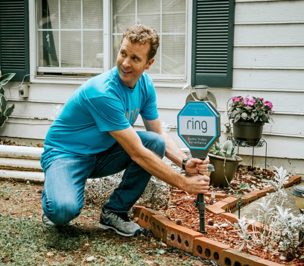 Jamie Siminoff places a Ring sign in a front yard
