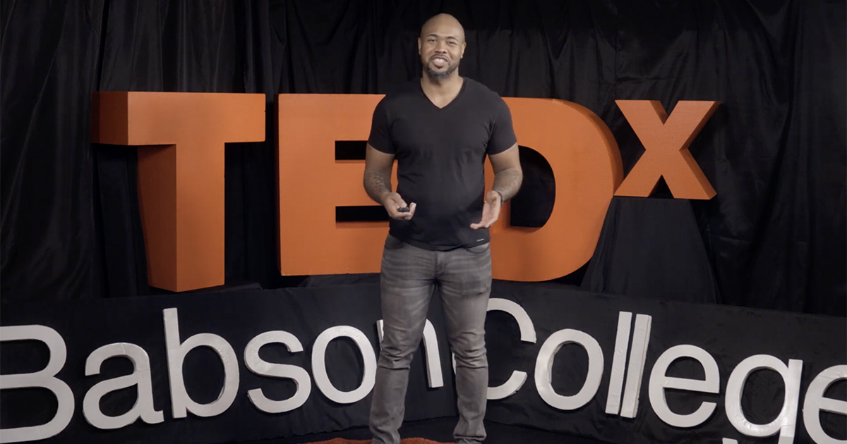 Google’s Calvin Pinney is pictured speaking on stage in front of a large TEDx Babson College sign.