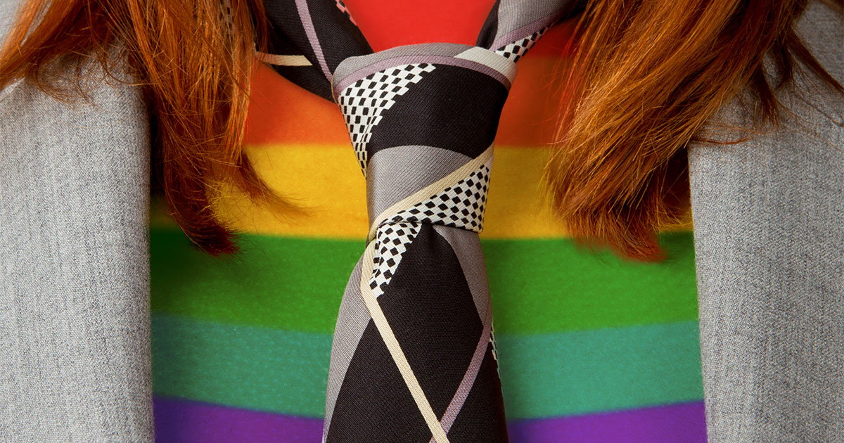 Close-up of a person wearing a suit jacket, tie, and a rainbow shirt