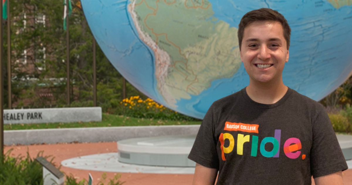 Ryan Findling stands in front of the Babson World Globe, wearing a shirt with its new logo on it.