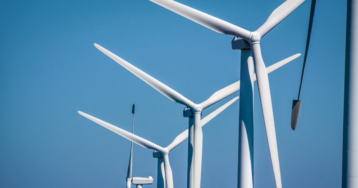 A row of wind turbines against a clear blue sky