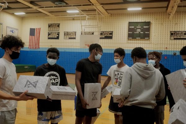 Thermidor, second from right, and the basketball team during his sneaker giveaway at Boston English High School.