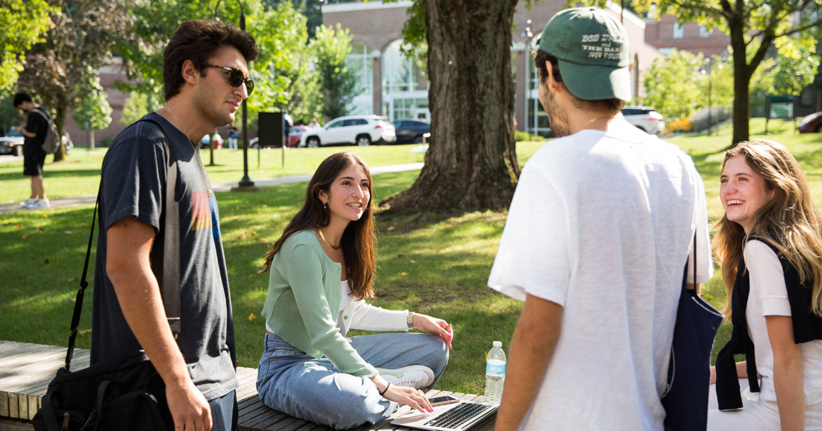 A group of four students talk outdoors on campus