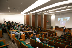A speaker addresses an audience in an auditorium.
