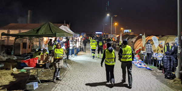 Volunteers walk among tents at night in Medyka, Poland