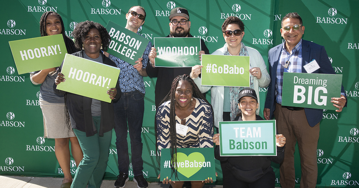 Babson staff members hold up signs at a recent campus event