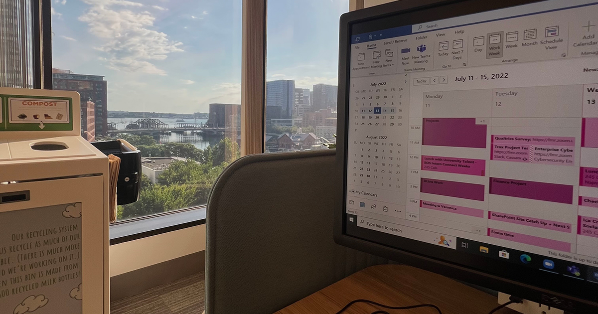 A computer showing a digital calendar next to the Boston skyline