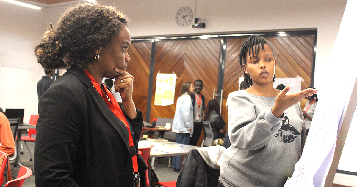 Wiljeana Glover works with a student at the hackathon