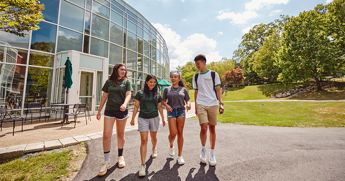 Four students walk on Babson's campus