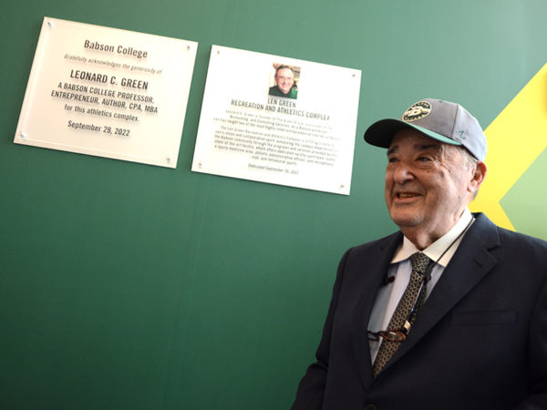 Len Green stands next to two plaques honoring him