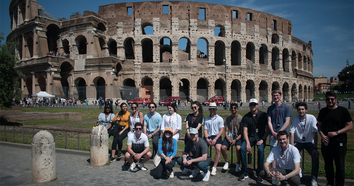 A group of Babson students gather for a photo before the Roman Colosseum