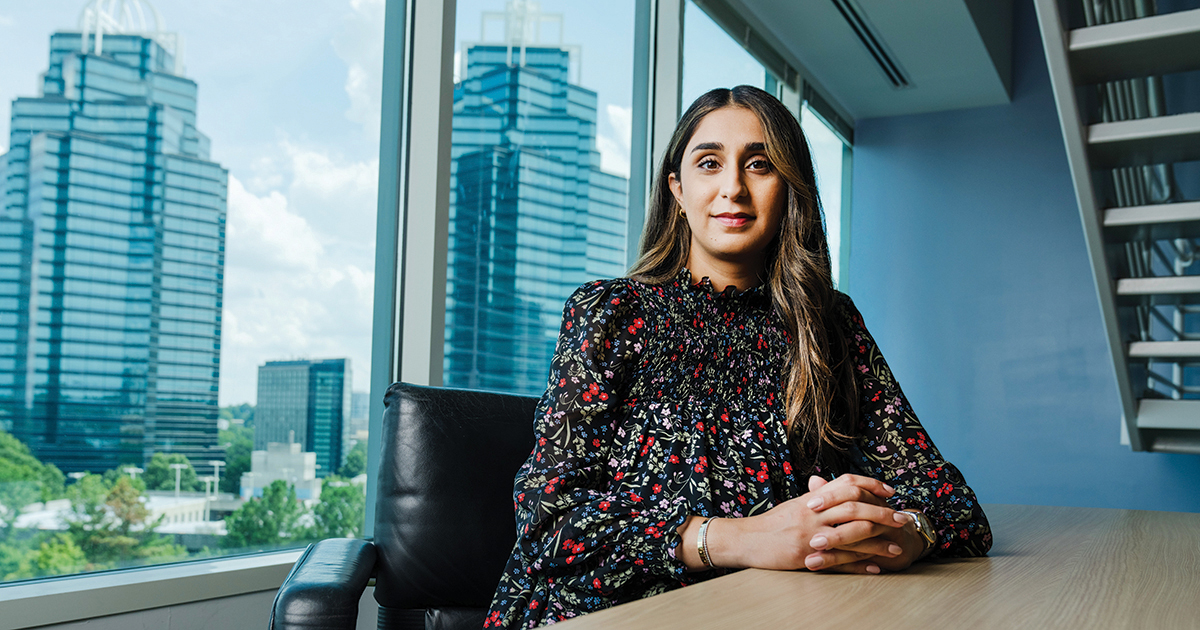 Somia Farid Silber sits at a conference room table with Atlanta skyline in the background