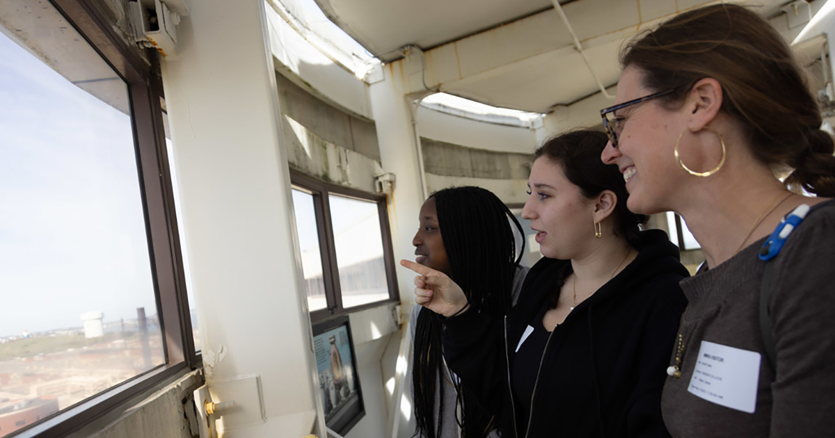 Two students and Professor Foster look out the window of the egg-shaped anaerobic digesters