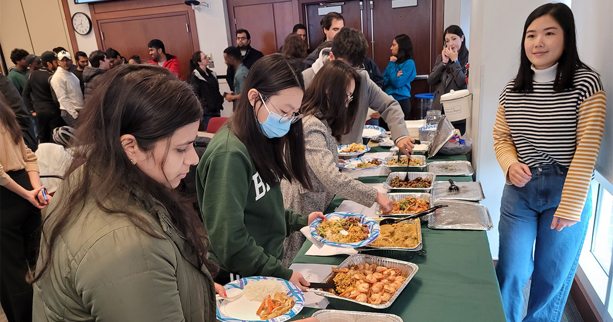 Students line up at a buffet table full of Thai food