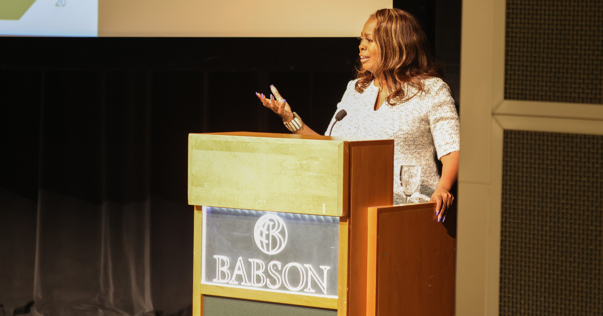 LaTosha Brown gestures while speaking behind a Babson podium
