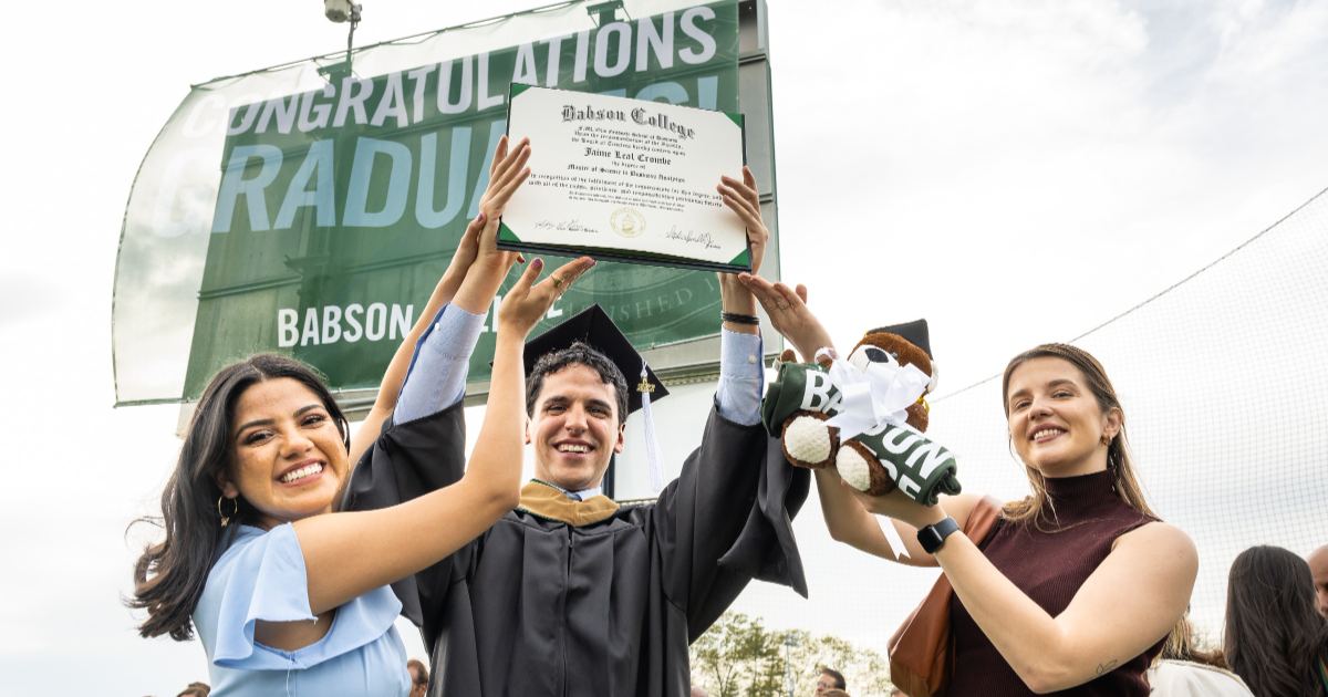 An MSBA graduate holds up his degree at Commencement