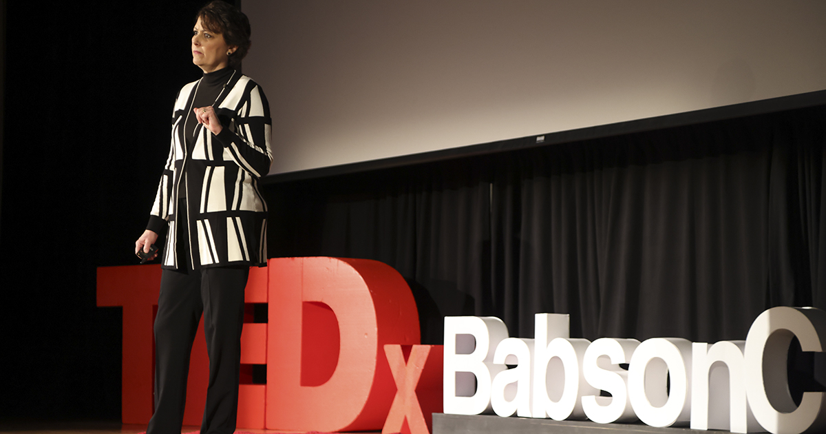 Woman speaking on stage at TEDxBabsonCollege