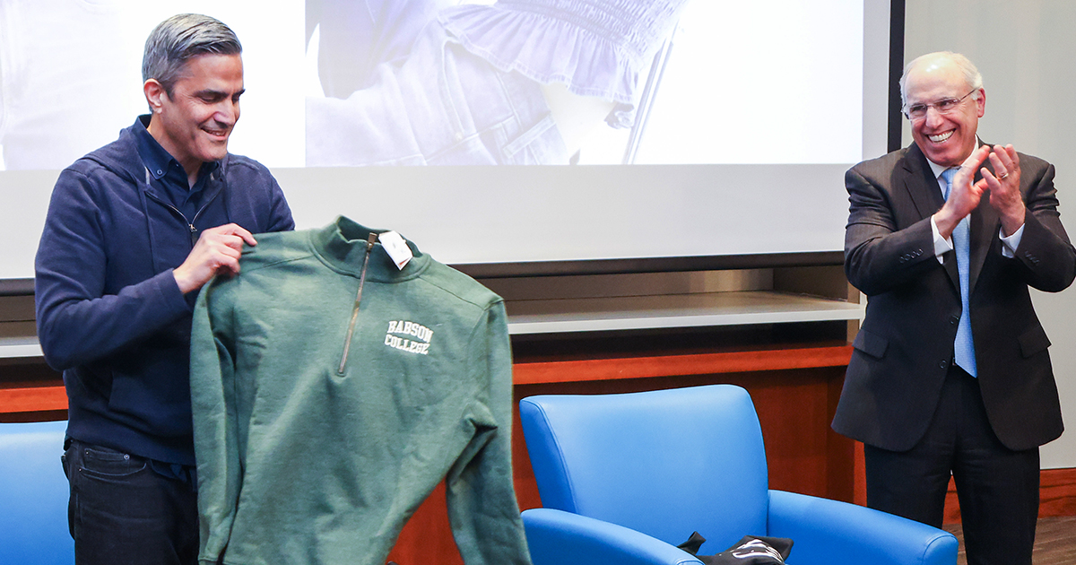 Mark Breitbard holds a Babson pullover he received as a gift while Stephen Spinelli looks on