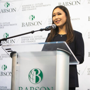 Joyce Wang speaks at a podium with Babson's logo