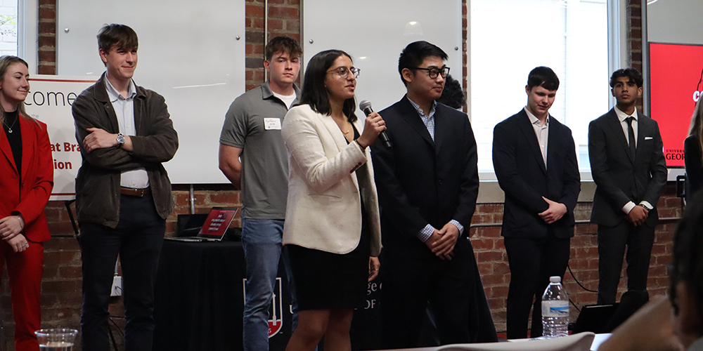 Babson students speaks at a competition standing in front of other competitors.