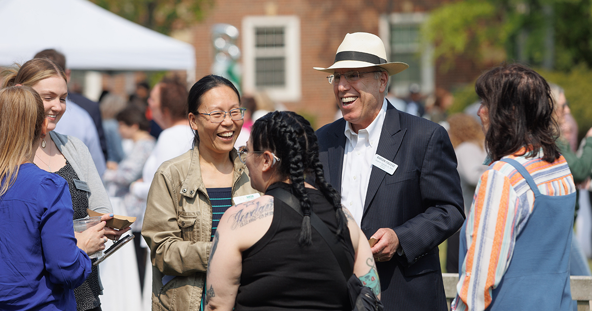 President Spinelli laughs while talking with Babson staff members