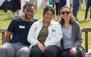 Three Babson staff members pose for a photo while sitting on a bench.