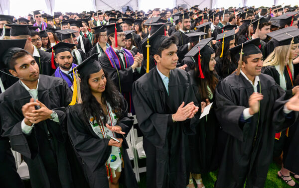 Graduates stand and applaud at Commencement