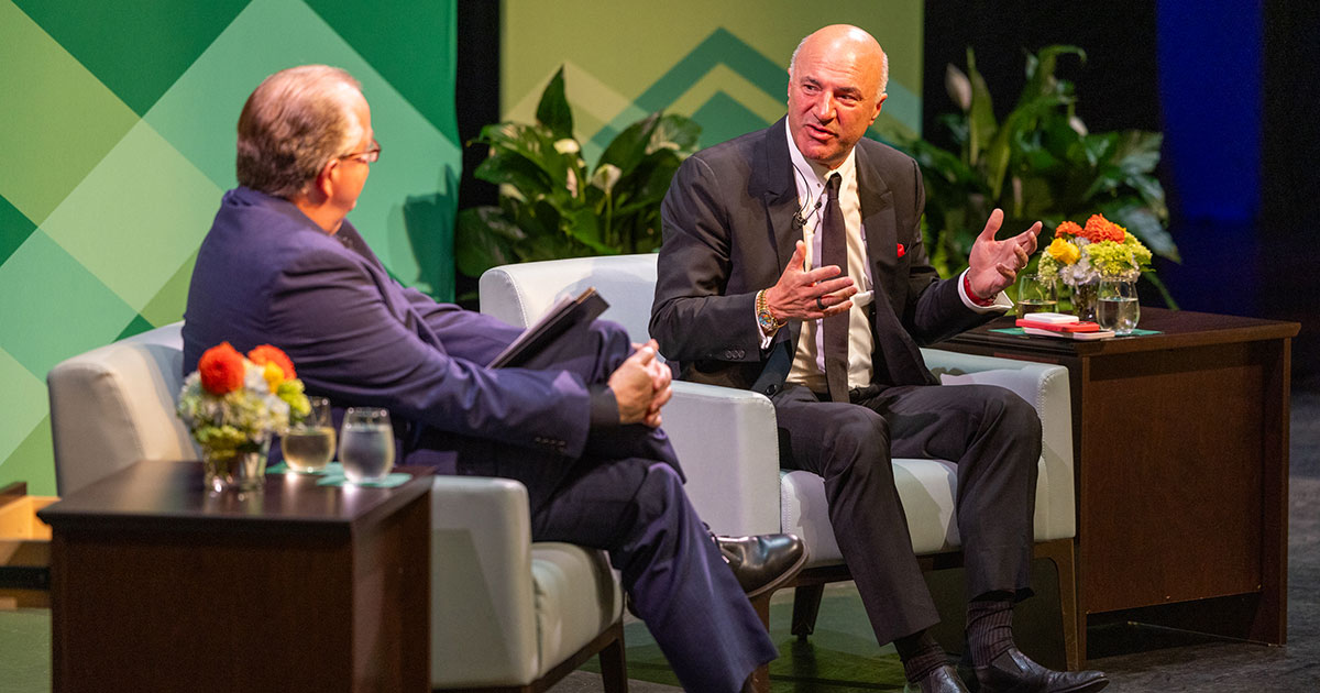 Jack McCarthy and Kevin O’Leary sit on chairs on the stage at Babson’s Sorenson Center for the Arts.