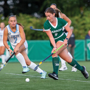 A Babson field hockey player tries to get around a Tufts defender