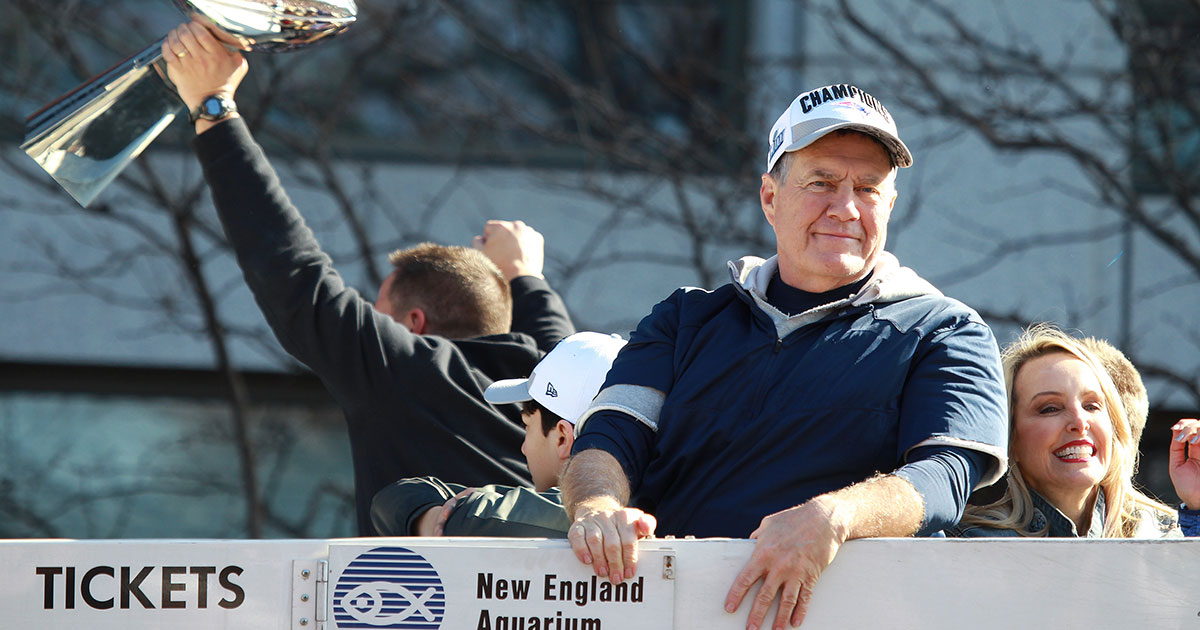 Bill Belichick looks to a camera as people around him celebrate a Super Bowl title