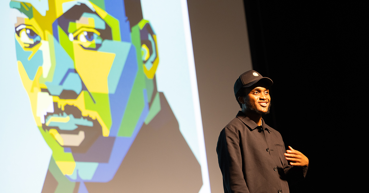 Wes Woodson smiles on stage in front of a colorful illustration of Martin Luther King Jr.
