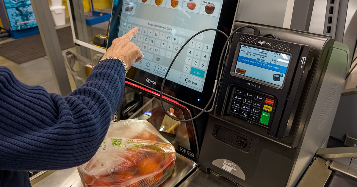 A woman uses self-checkout at a grocery store.