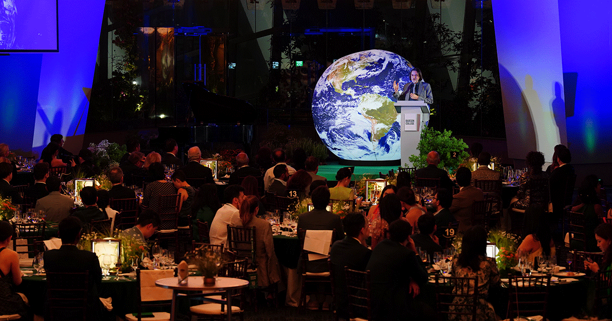 Cyril Camus addresses a room full of people sitting at tables while behind him is a model globe