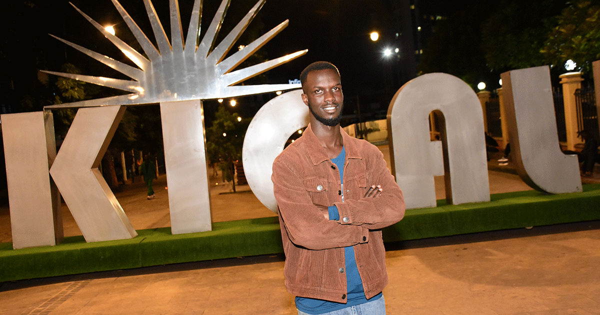Alcade Fabrice Uwonkunda stands in front of a sculpture of the word Kigali