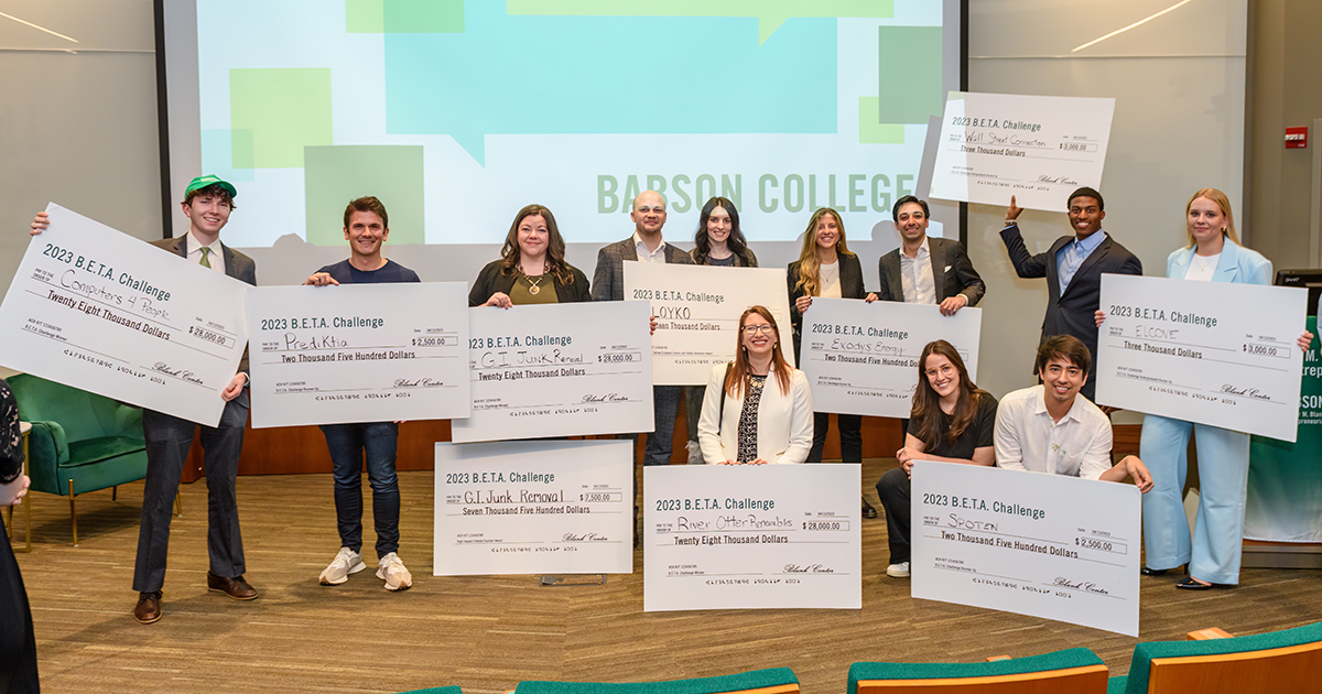 A group of 12 B.E.T.A. Challenge participants hold up their winning checks