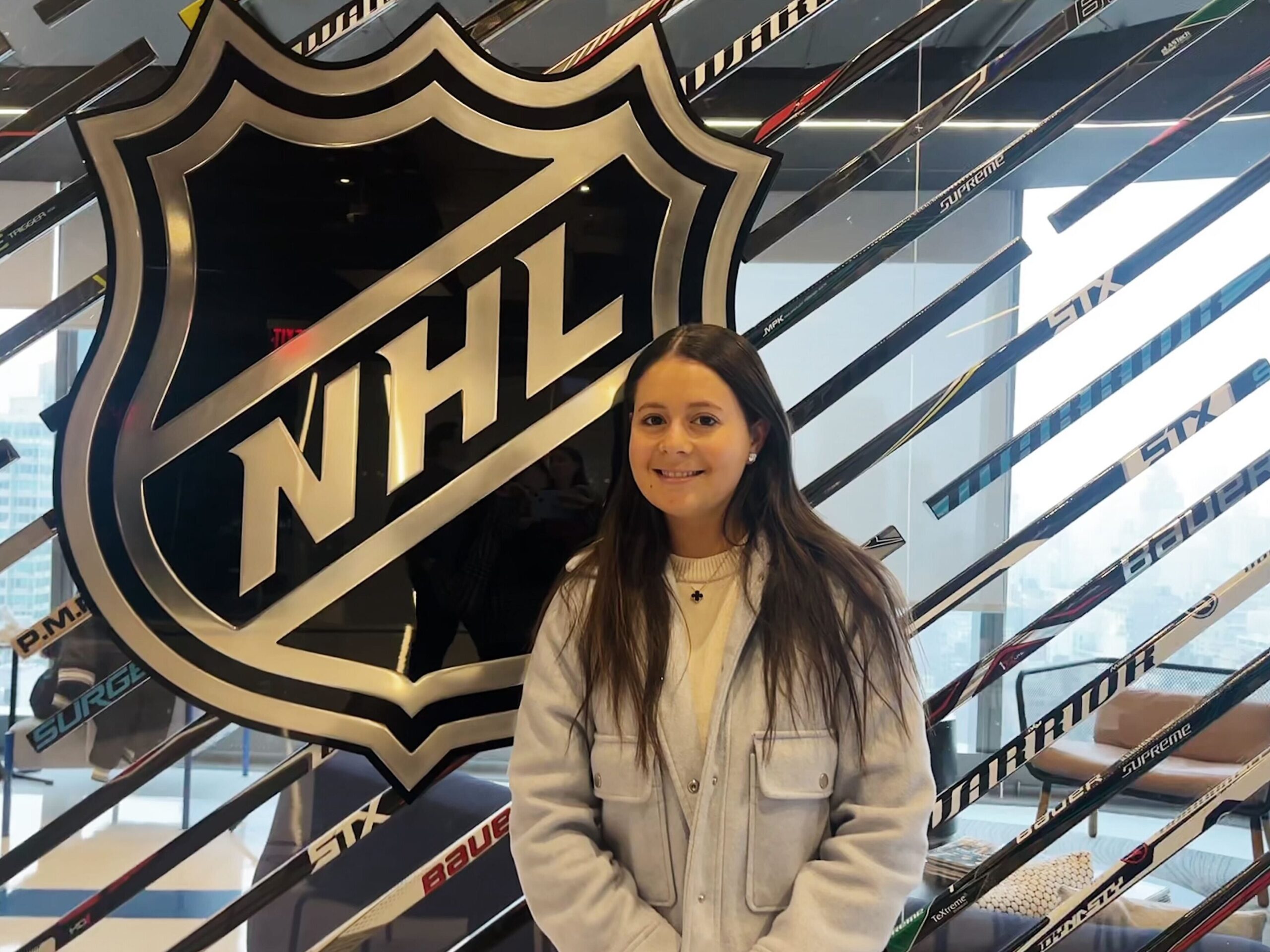 Shay Koss in front of a sign of the NHL logo