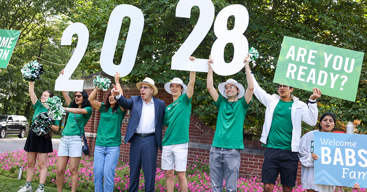 Students and President Spinelli hold up 2028 sign at the front gate