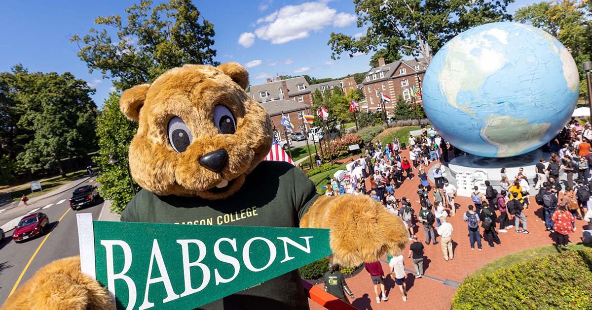 The Babson mascot holds a Babson pennant with the community congregating around the Babson Globe