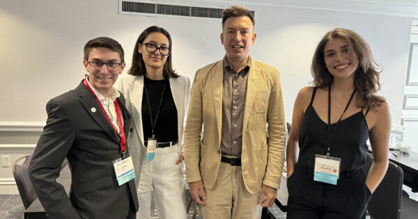 Three students and a professor pose for a group photo at the conference