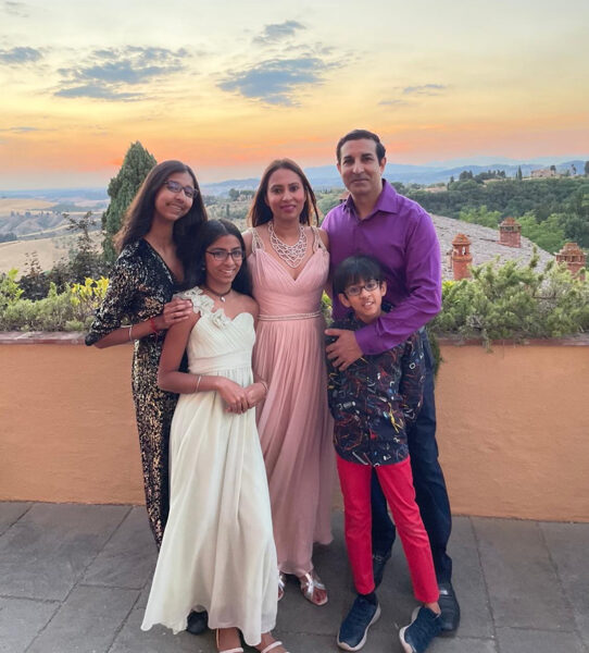 The family poses for a photo in front of a sunset at Castelfalfi