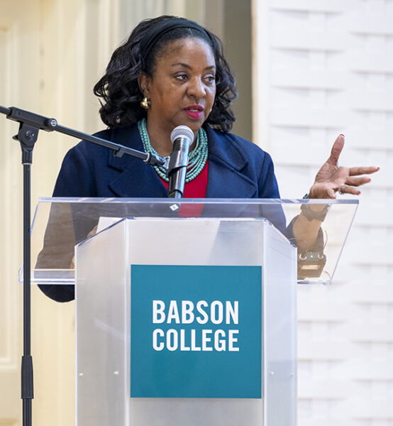 Sadie Burton-Goss gestures while speaking behind a podium