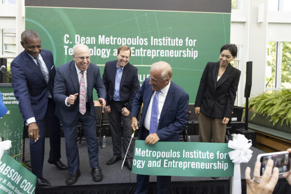 C. Dean Metropoulos cuts the ribbon at the ceremony with other dignitaries on stage