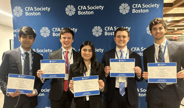 A group of five students pose for a photo with their winning certificates