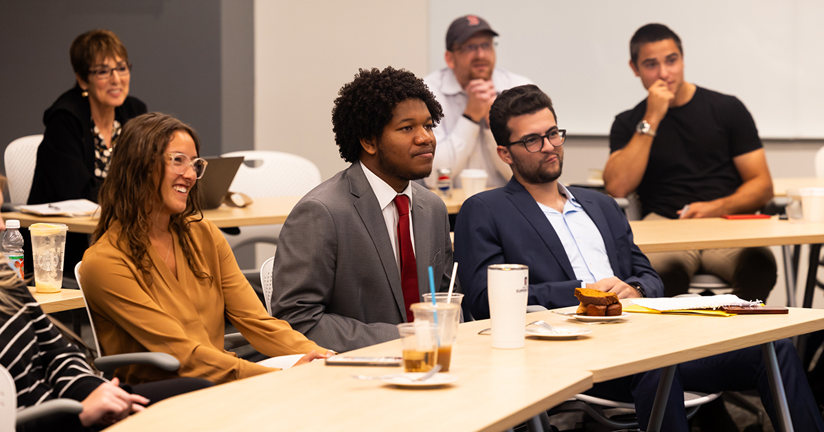 Engaged students are seated at tables during a classroom presentation