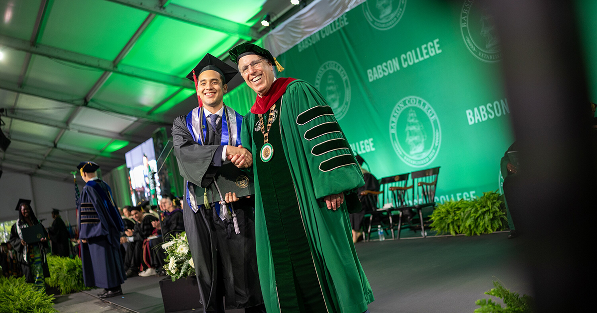 College president shakes hands with a student at the Commencement ceremony