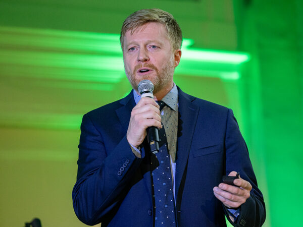 Trond Undheim speaks from the stage with green lights behind him