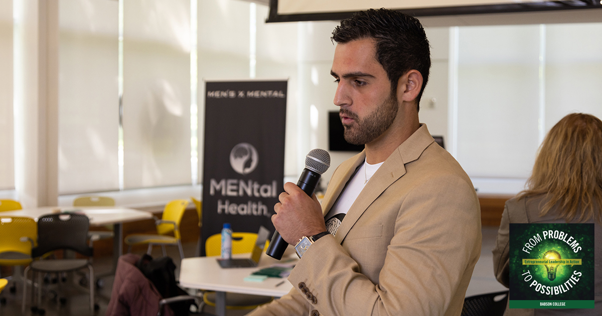 Teddy Sourlis holds a microphone while speaking at an event