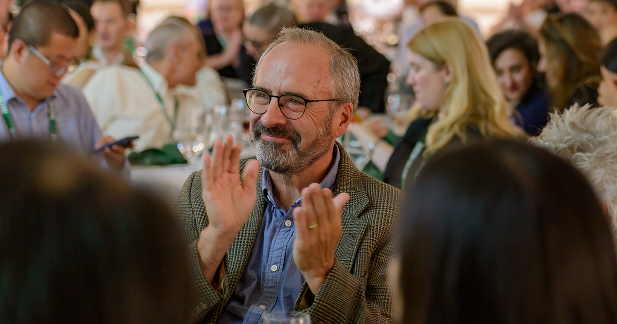 Andrew “Zach” Zacharakis applauds while sitting at a table during a BCERC dinner