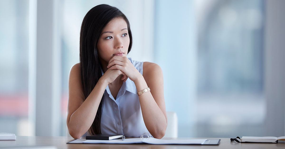 A woman sits at a desk and thinks