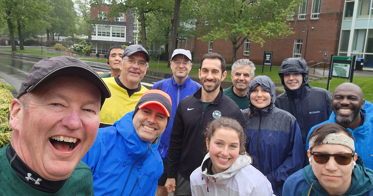 Runners pose for a photo on a rainy day at Babson